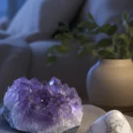 An amethyst and a piece of howlite resting on a folded linen cloth on a nightstand beside a dim bedside lamp, soft moonlit blue tones, calm bedroom