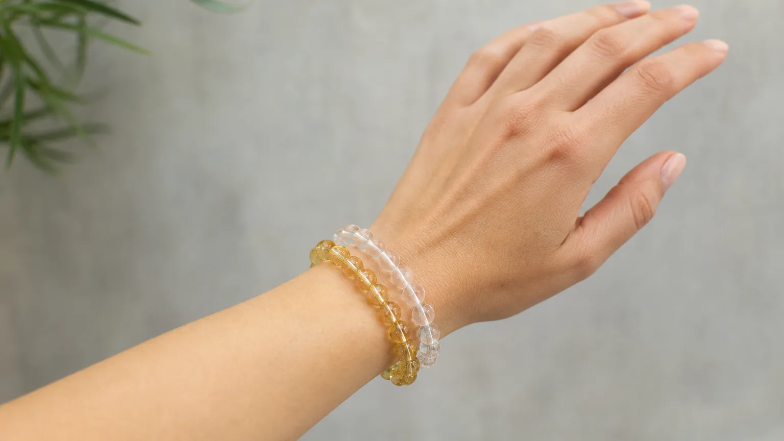 Quartz and Citrine crystal bracelets worn together stacked on one wrist, real hand, natural daylight, minimalist wellness lifestyle scene