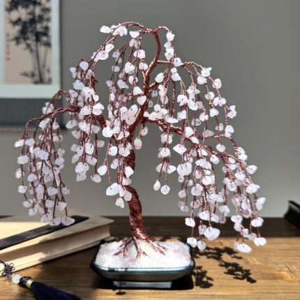 May include: A pink crystal wire wrapped willow tree with a copper wire trunk and branches. The tree is in a black pot with a base of pink crystals.