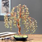 May include: A copper wire sculpture of a weeping willow tree with green glass beads for leaves. The tree is in a black ceramic pot with a green base.
