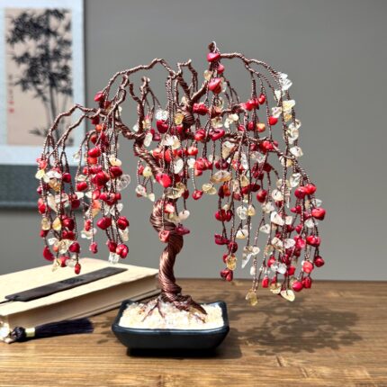 May include: A handcrafted bonsai tree sculpture with a copper wire trunk and branches. The branches are adorned with red, yellow, and clear gemstone beads, creating a cascading effect. The tree sits in a small, square black pot.