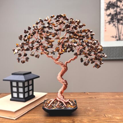 May include: A decorative wire tree sculpture featuring a twisted copper-colored trunk and branches adorned with numerous small, polished brown and gold tiger's eye gemstone chips, set in a square black base filled with matching stone fragments.