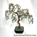 May include: A green aventurine and citrine wire wrapped tree with a black square pot. The tree has a twisted trunk and cascading branches.