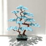 May include: A wire-wrapped tree sculpture with blue aquamarine crystals and a copper wire base. The tree is in a black pot with a blue crystal base.