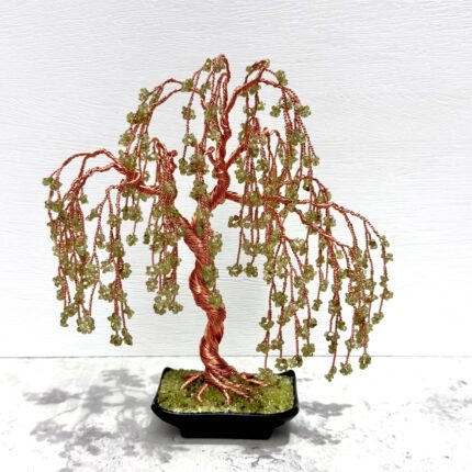 May include: A copper wire sculpture of a weeping willow tree with green gemstone leaves. The tree is in a black pot with a green gemstone base.